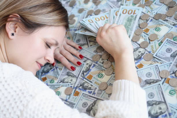 Woman with money in her hands sleeping on dollar bills. Happiness in money concept