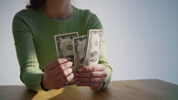 Successful woman hands checking amount of cash money at table closeup. Unrecognizable businesswoman holding two dollar bills indoors. Unknown lady enjoying banknotes counting salary. Payment concept